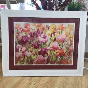 Un puzzle floral enmarcado en un cuadro blanco y con fondo granate.