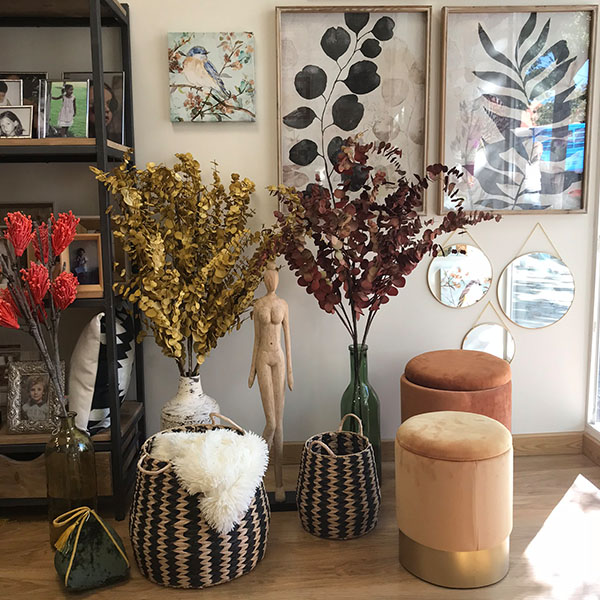 Foto de un mueble con varios marcos de fotos, espejos, cestas de mimbre y plantas secas.